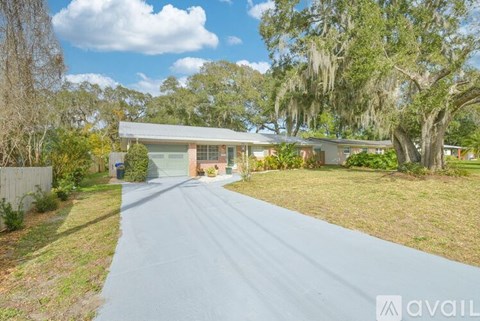 A house with a driveway in front of it surrounded by trees.