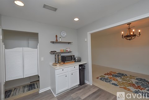 A kitchen with white cabinets and a black trash can.