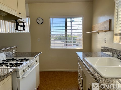 A kitchen with a white stove and a window with blinds.