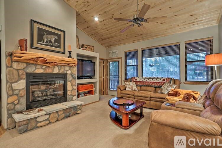A living room with a stone fireplace and a flat screen TV.