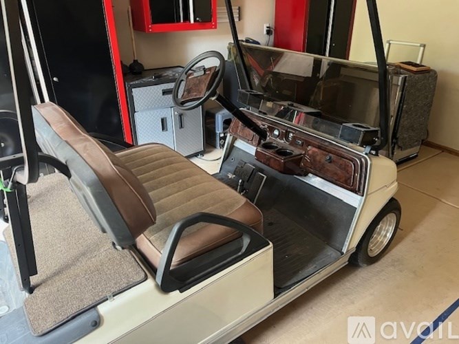 A golf cart with brown leather seats is parked indoors.