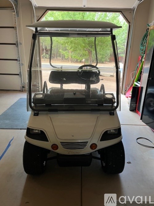 A white golf cart is parked inside a garage.