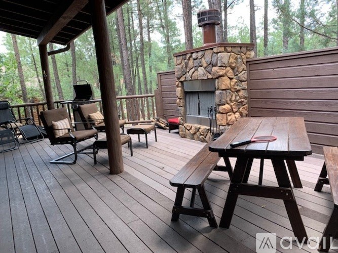 A wooden deck with a table and chairs and a stone fireplace.