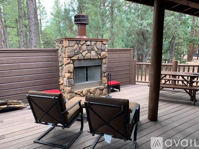 Two chairs are on a wooden deck in front of a stone fireplace.