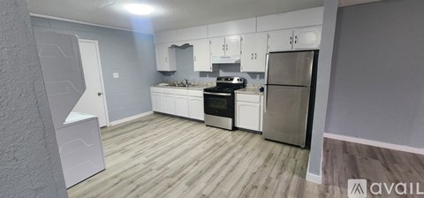 A kitchen with white cabinets and a refrigerator.