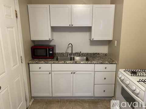 A kitchen with white cabinets and a black microwave above the sink.