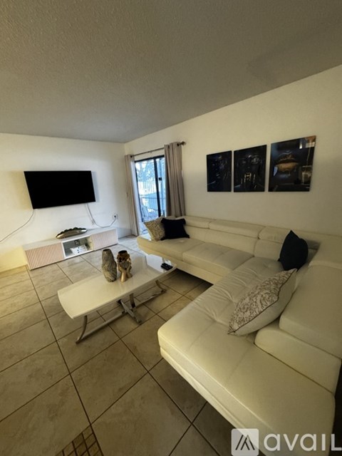 A living room with a white couch and a television on the wall.