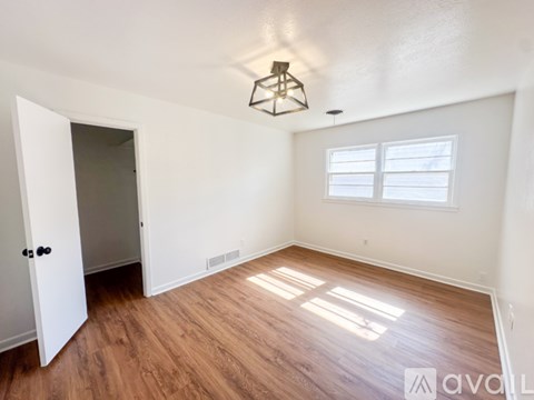 A room with wooden flooring and a window with blinds.