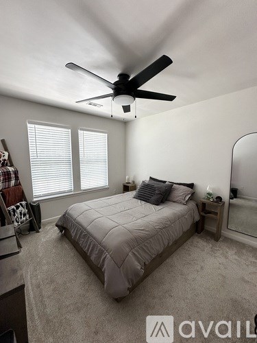 A bedroom with a bed, a ceiling fan, and a window with blinds.