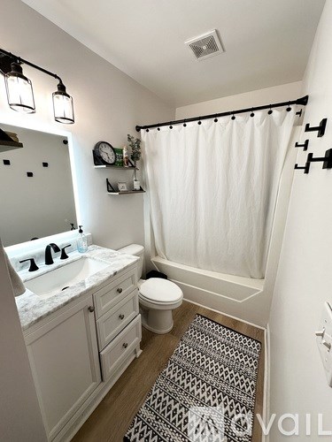 A bathroom with a white sink, toilet, and shower curtain.