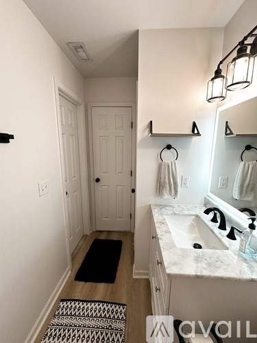 A bathroom with a sink, mirror, and towel racks.