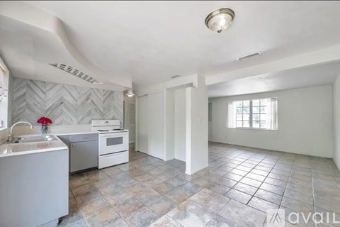 A kitchen with a sink, stove, and a window.