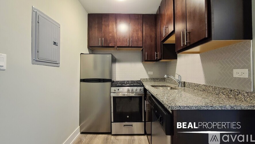 A kitchen with a stainless steel refrigerator and a granite countertop.