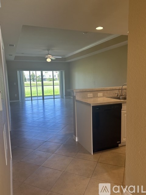 A kitchen with a black dishwasher and a ceiling fan.