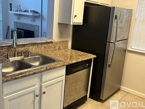 A kitchen with a black refrigerator and a granite countertop.