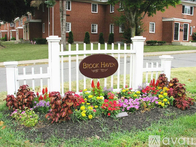 A white picket fence with a sign that says Brook Haven.