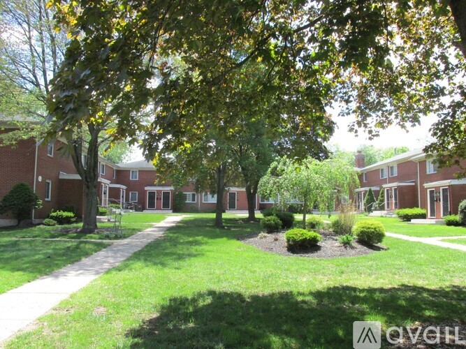 A tree-lined walkway leads to a building.