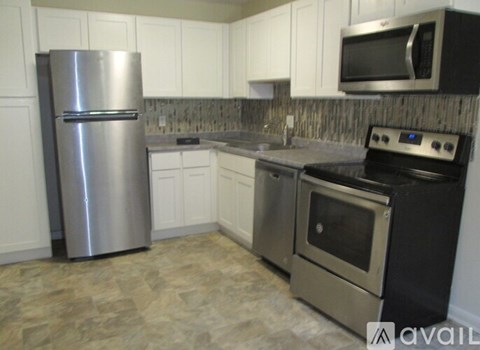 A kitchen with a stainless steel refrigerator, microwave, oven, and cabinets.