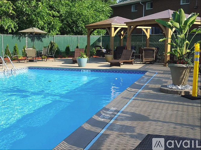 A pool with a wooden deck and a gazebo in the background.