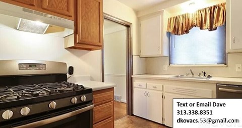 A kitchen with a black stove top oven and wooden cabinets.