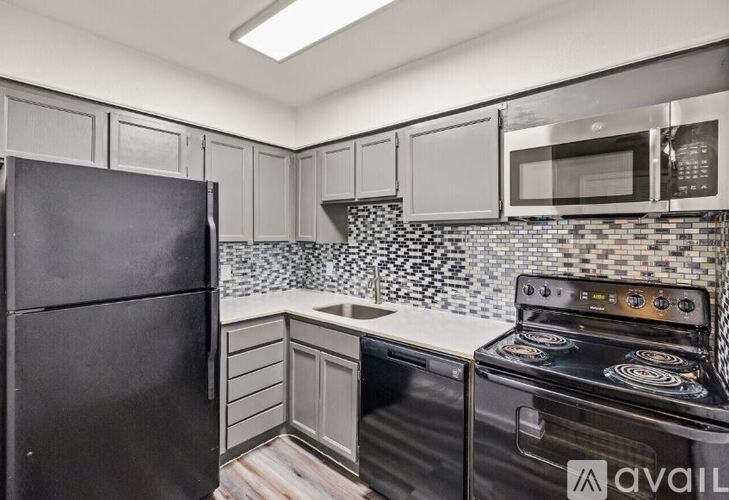 A kitchen with a black refrigerator, black oven, and a black microwave.