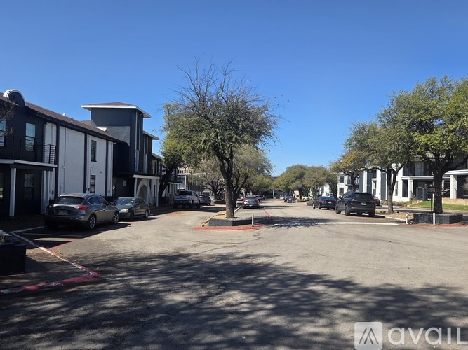 A sunny day in a parking lot with cars and buildings.