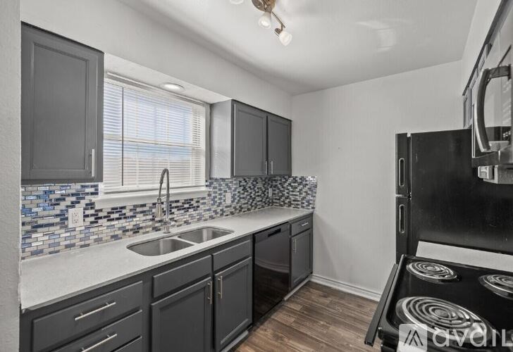A kitchen with black cabinets and a black fridge.