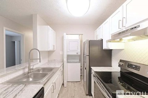 A kitchen with a stove, sink, and refrigerator.