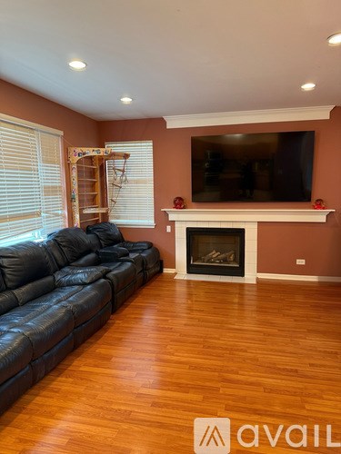 A living room with a black leather couch and a fireplace.