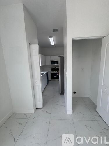 A kitchen area with white cabinets and a marble floor.