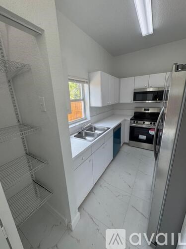 A kitchen with white cabinets and a stainless steel refrigerator.