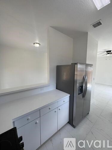 A kitchen with white cabinets and a stainless steel refrigerator.