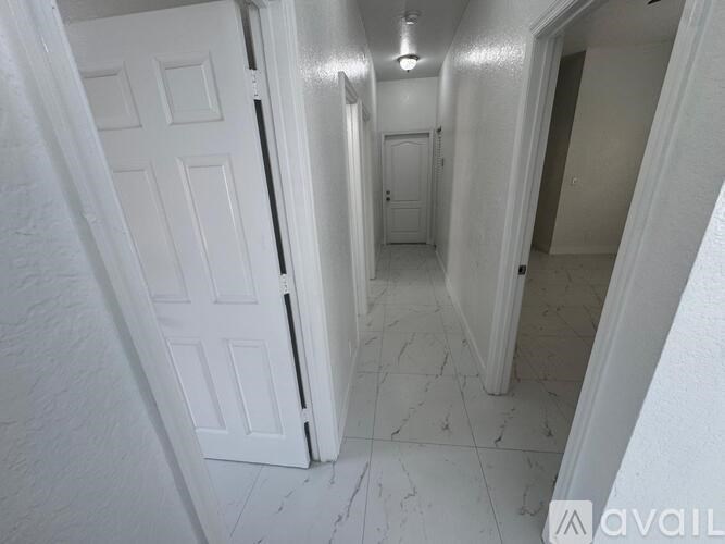 A hallway with white doors and marble floors.