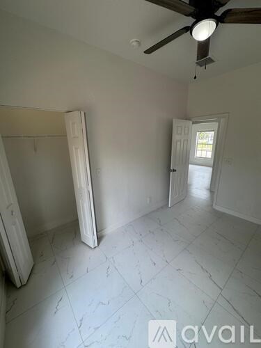 A room with a ceiling fan and a door leading to another room.