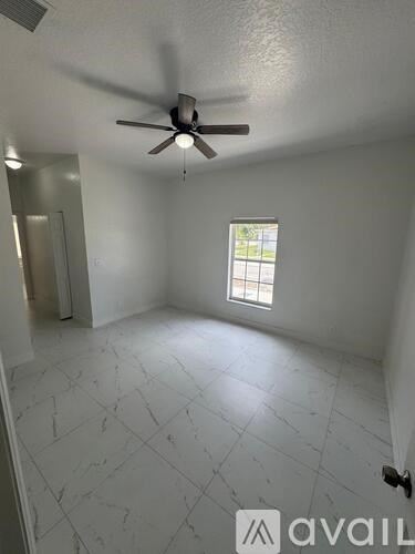 A room with a ceiling fan and a window.