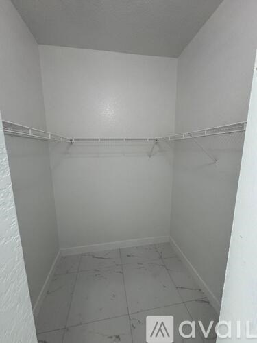 A small, empty room with a white wall and a white floor.
