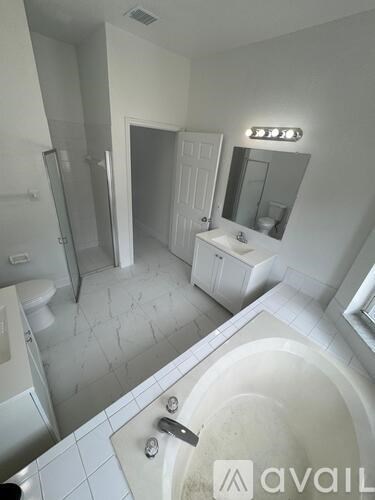 A bathroom with a tub, sink, mirror and toilet.