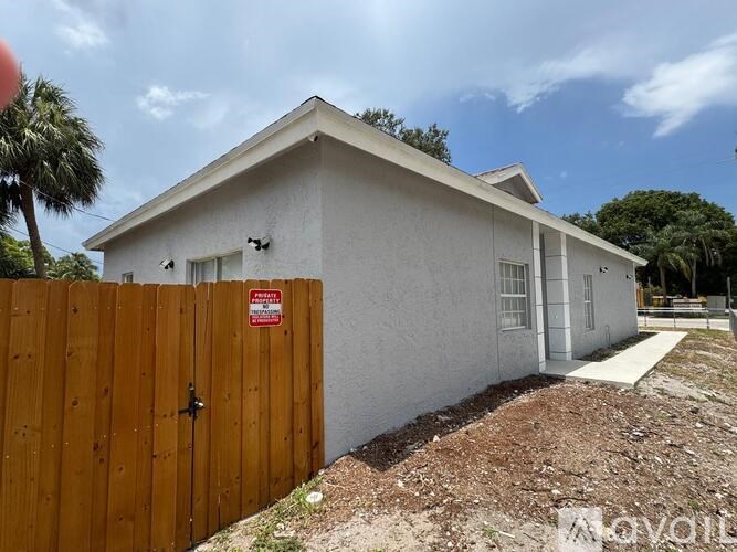 A white house with a brown fence and a sign on it.