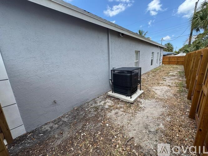 A white building with a black air conditioning unit in front.