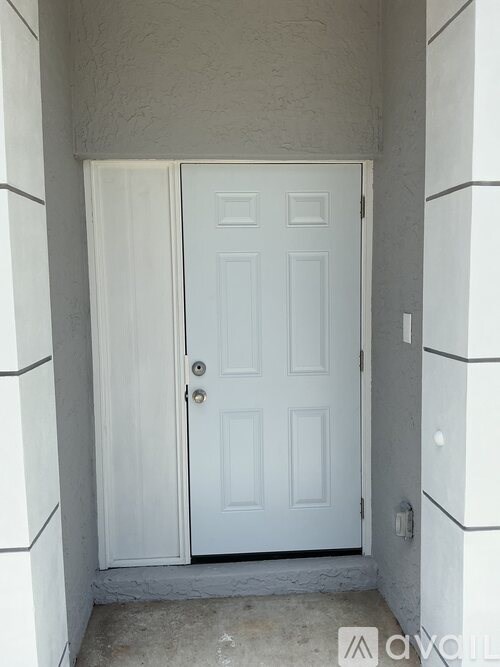 A white door is in a hallway with white walls.
