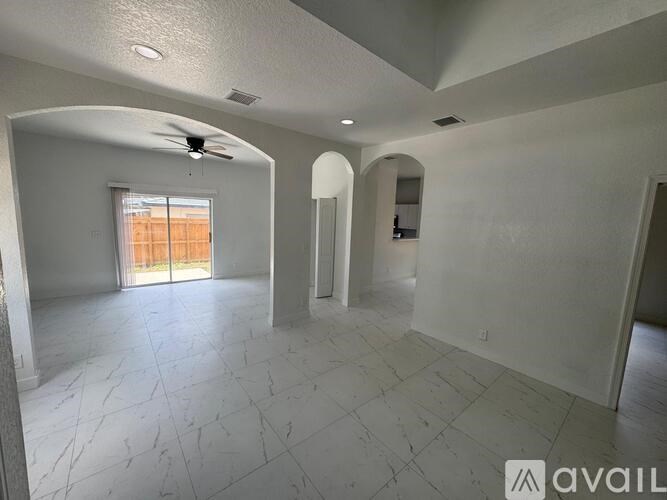 A spacious room with a ceiling fan and a large window.