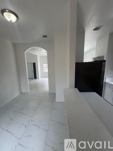 A hallway with white marble flooring and a black cabinet.