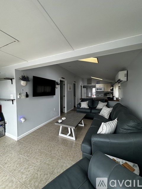 A living room with a grey couch and a flat screen TV mounted on the wall.