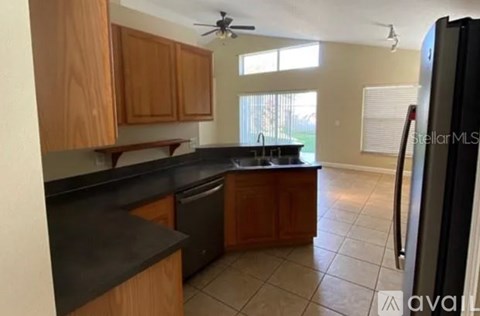 A kitchen with wooden cabinets and black countertops.