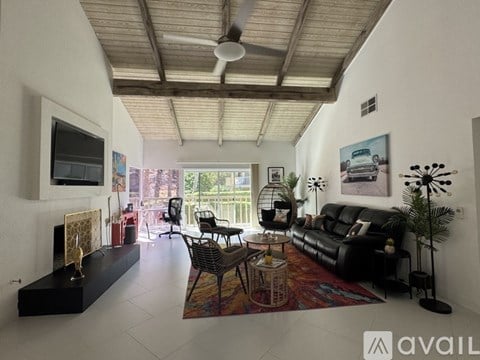 A living room with a black couch and a television on the wall.