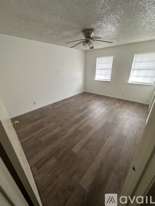 A room with wooden flooring and a ceiling fan.