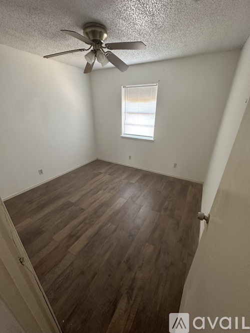 A room with a ceiling fan and wooden flooring.