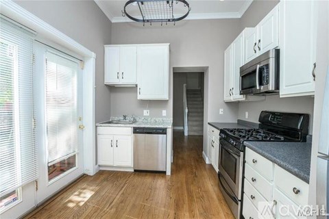 A kitchen with white cabinets and a black stove top.