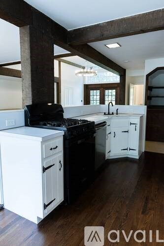 A kitchen with white cabinets and black appliances.