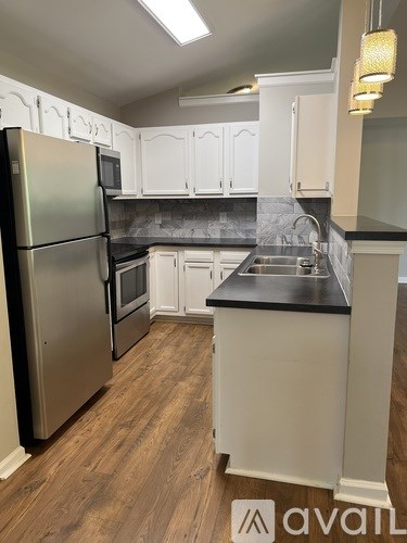 A kitchen with a stainless steel refrigerator and white cabinets.